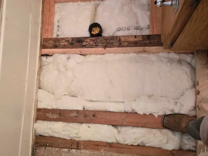 Opened floor showing joists and insulation during an under-floor repair