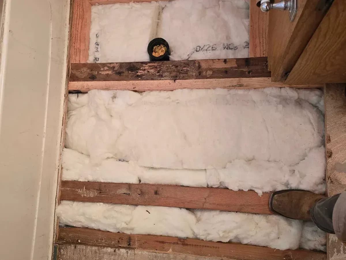 Opened floor showing joists and insulation during an under-floor repair