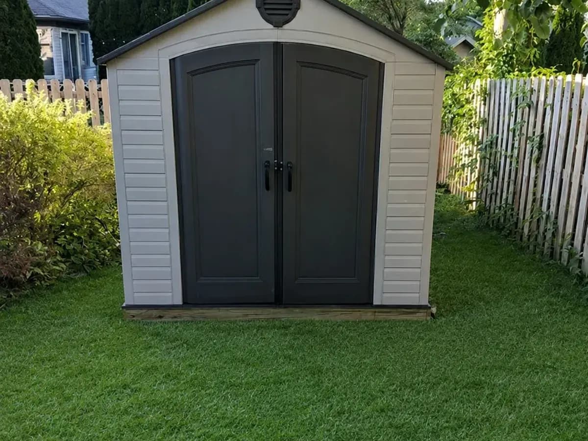 Assembled storage shed with double doors in a backyard