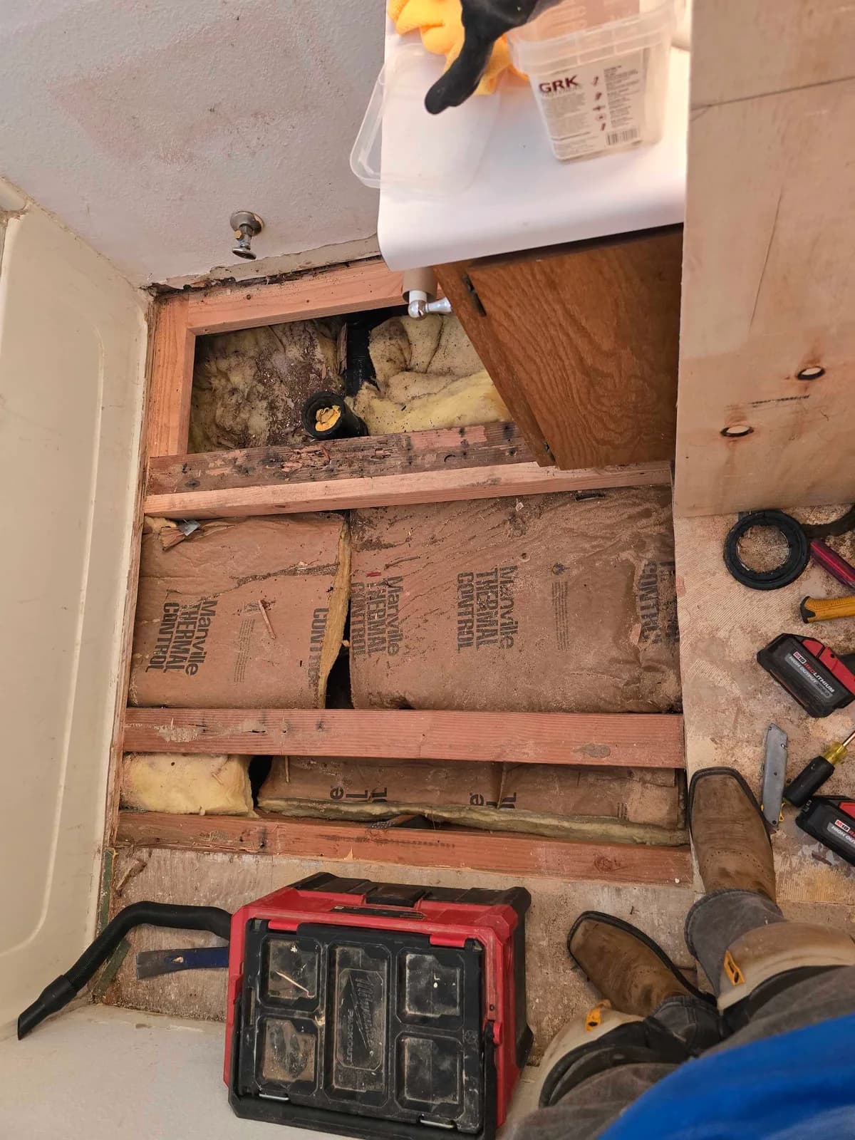 Opened bathroom floor with exposed joists, insulation and a toilet drain opening