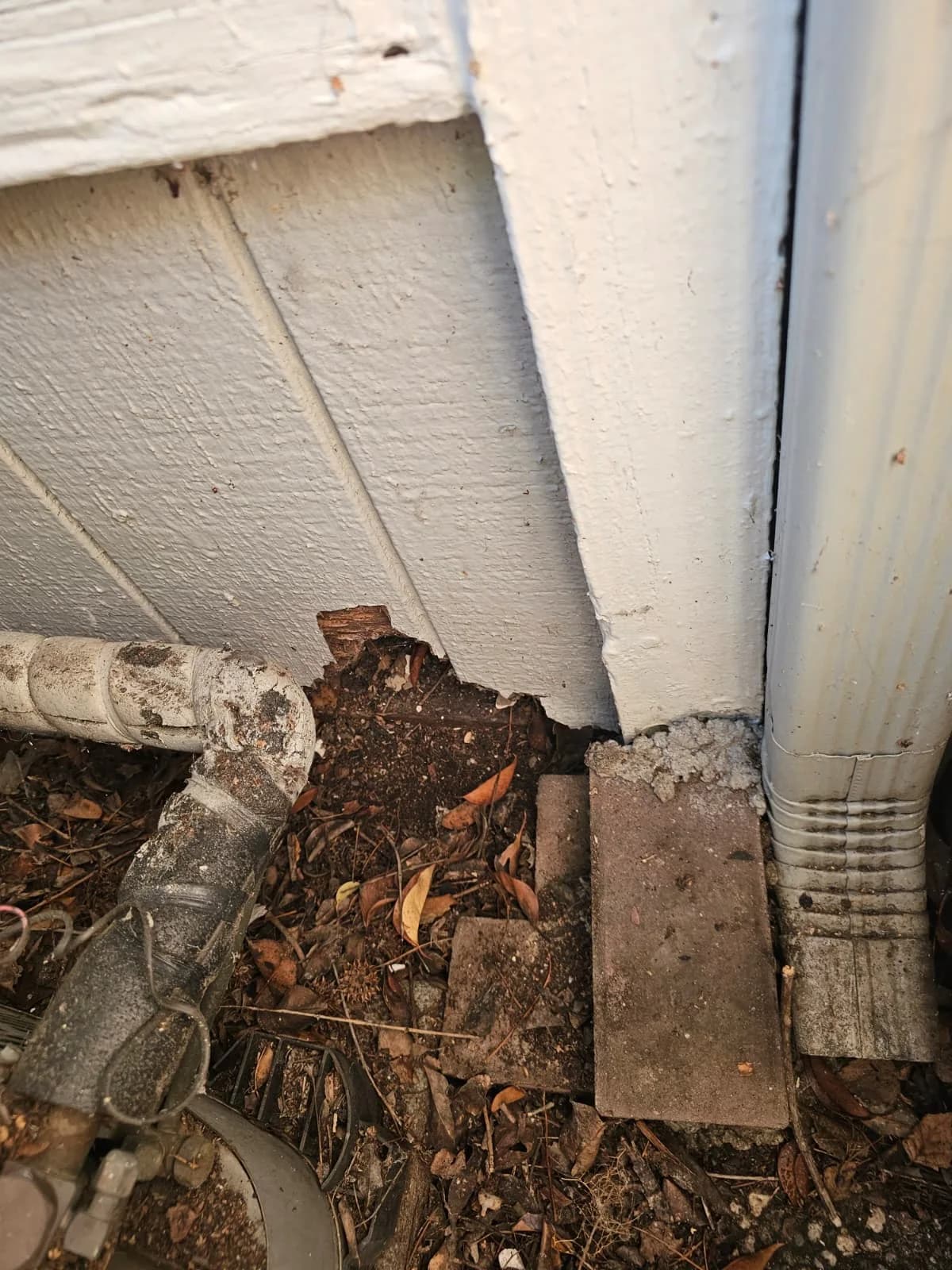 Close view of a crumbling exterior wood corner with an open joint and moisture damage