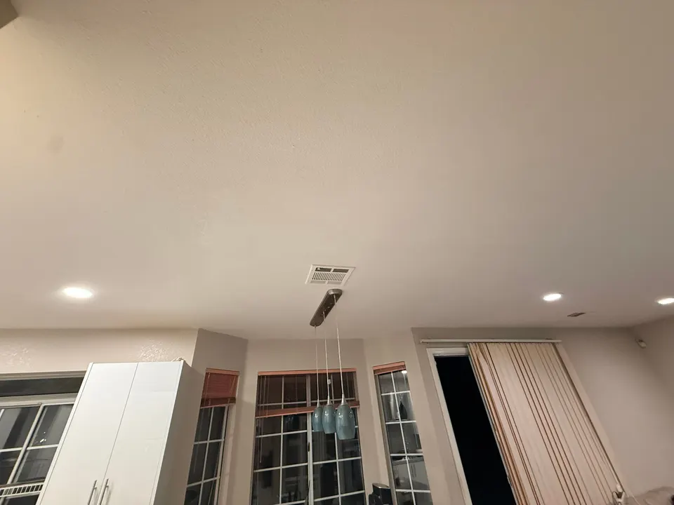 Finished light-colored ceiling above windows and curtains
