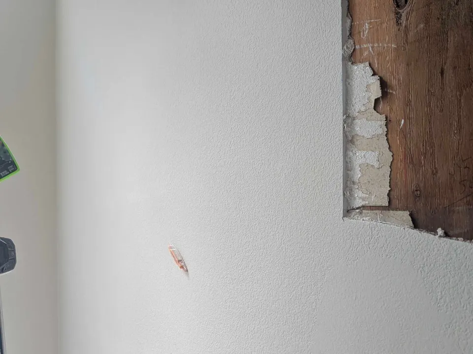 Interior wall with an opened section beside existing white drywall