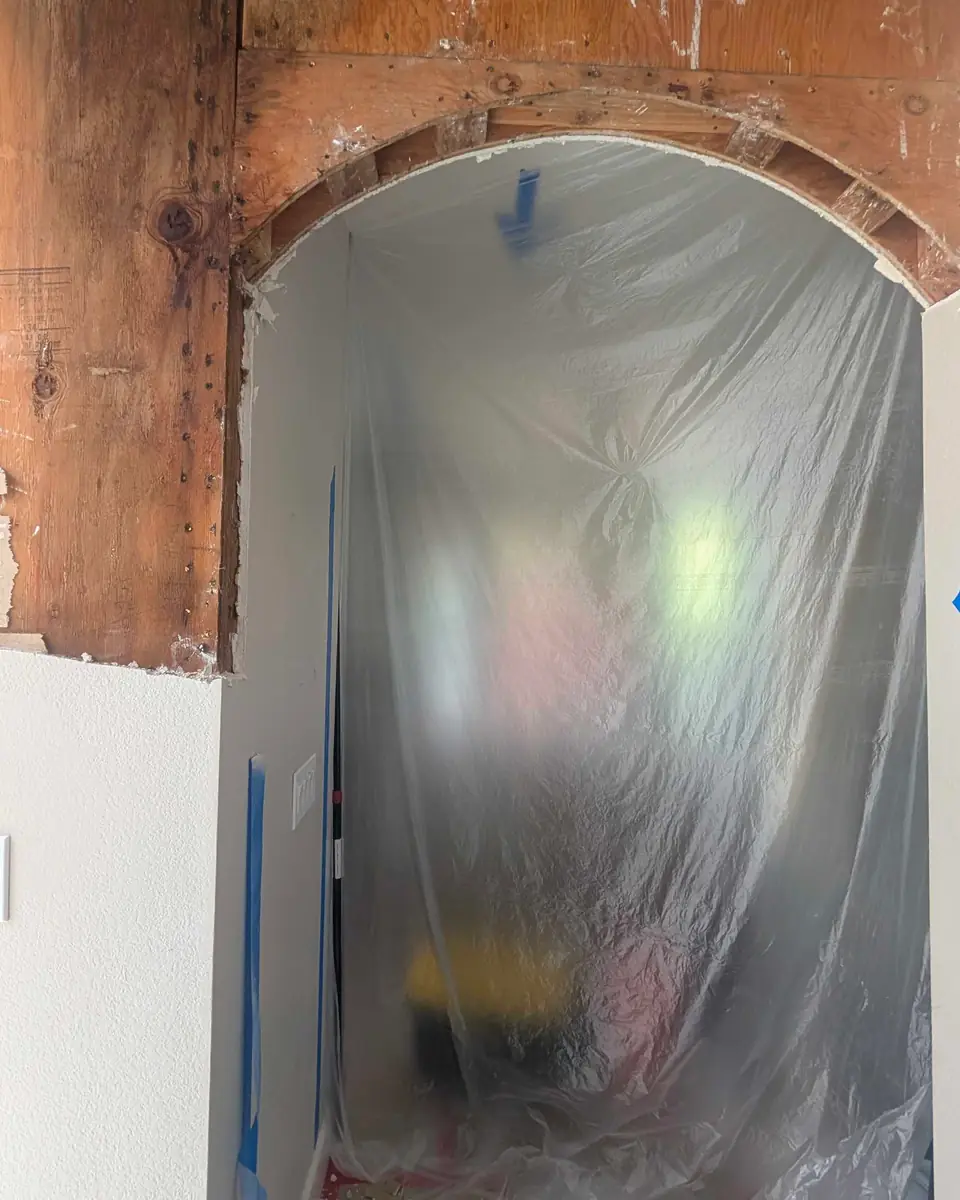 Interior arch opened to expose wood framing during drywall restoration