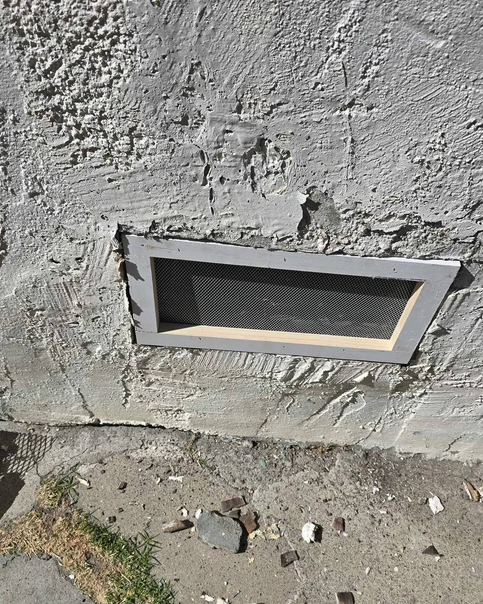 Completed exterior wall repair surrounding a low rectangular vent