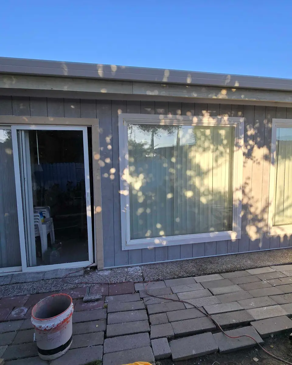 Completed exterior wall with new grey panel siding and white trim