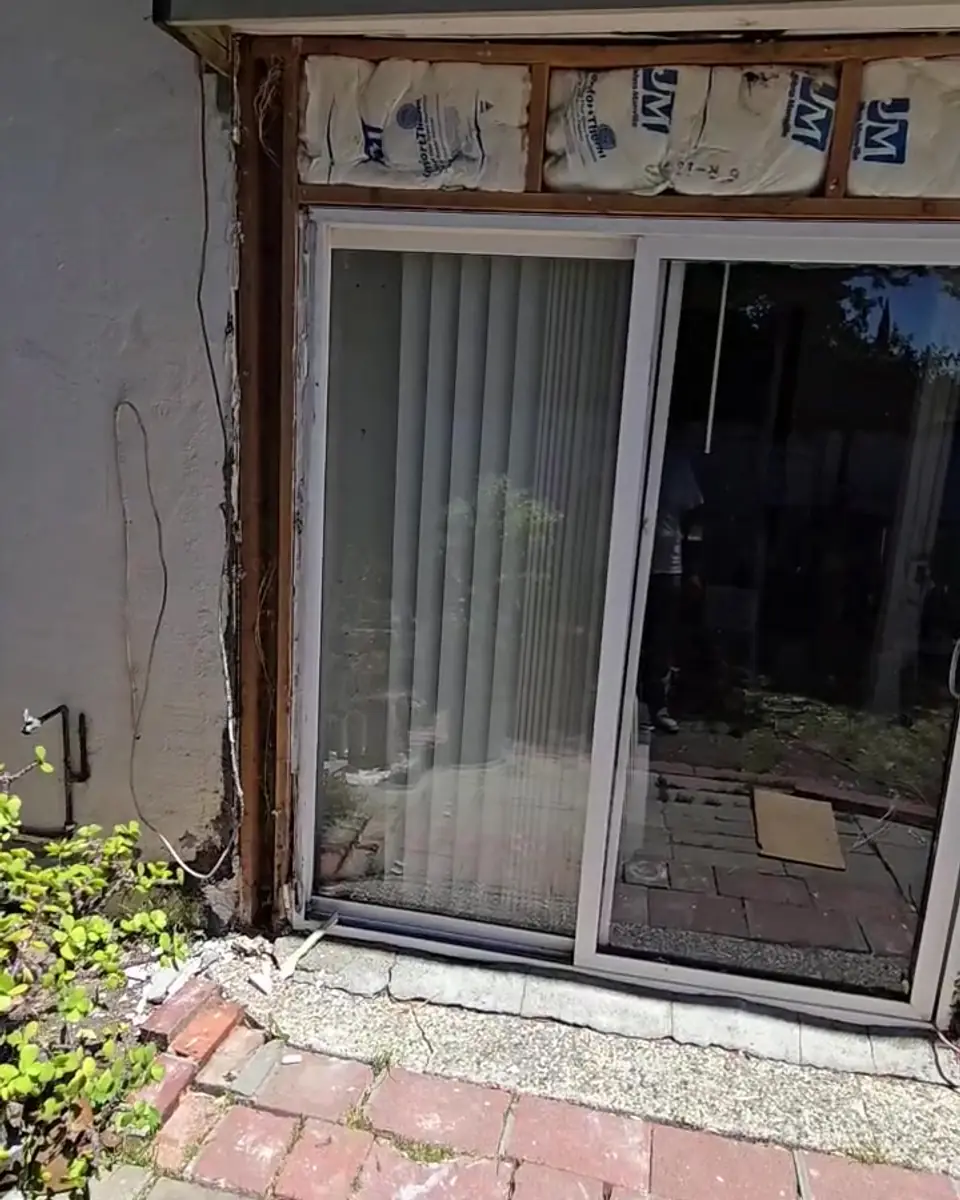 Exterior wall opened beside a sliding door during dry-rot repair