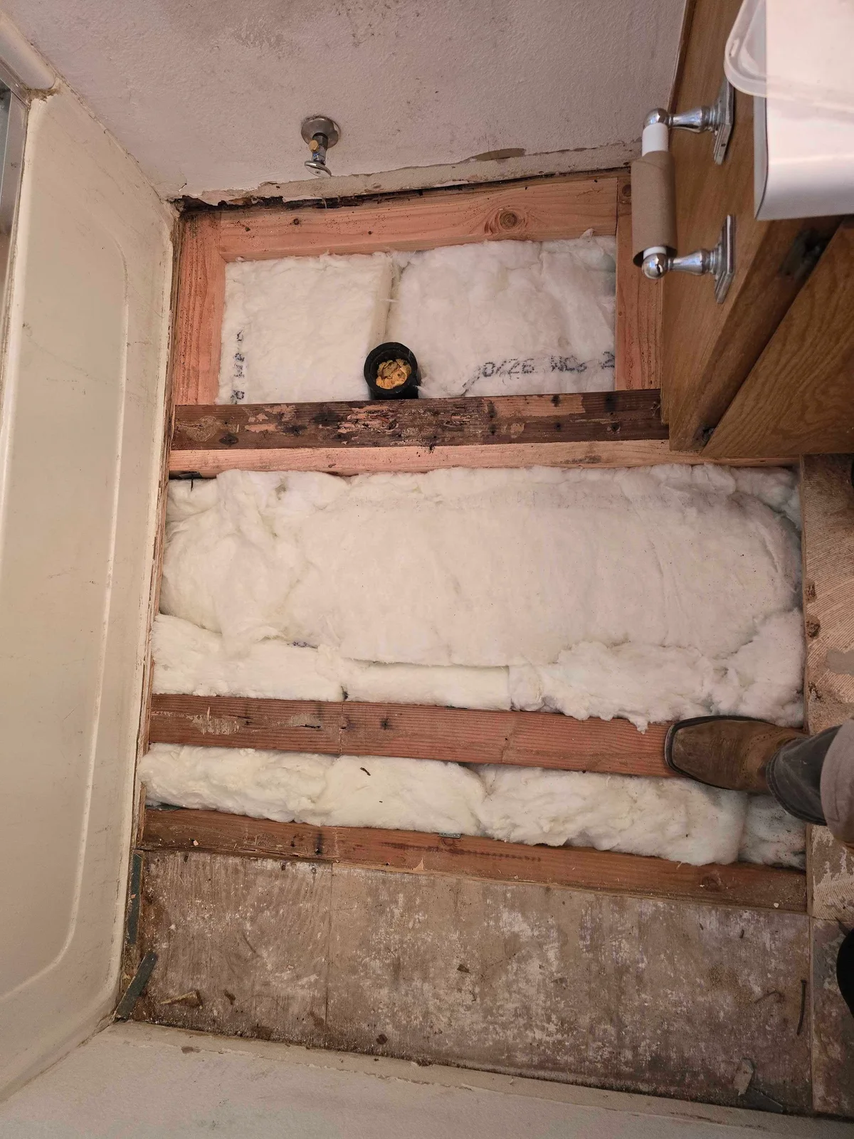 Exposed bathroom floor joists and insulation